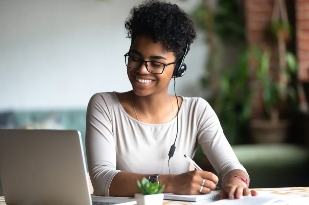Femme souriante coupe afro ordinateur cahier