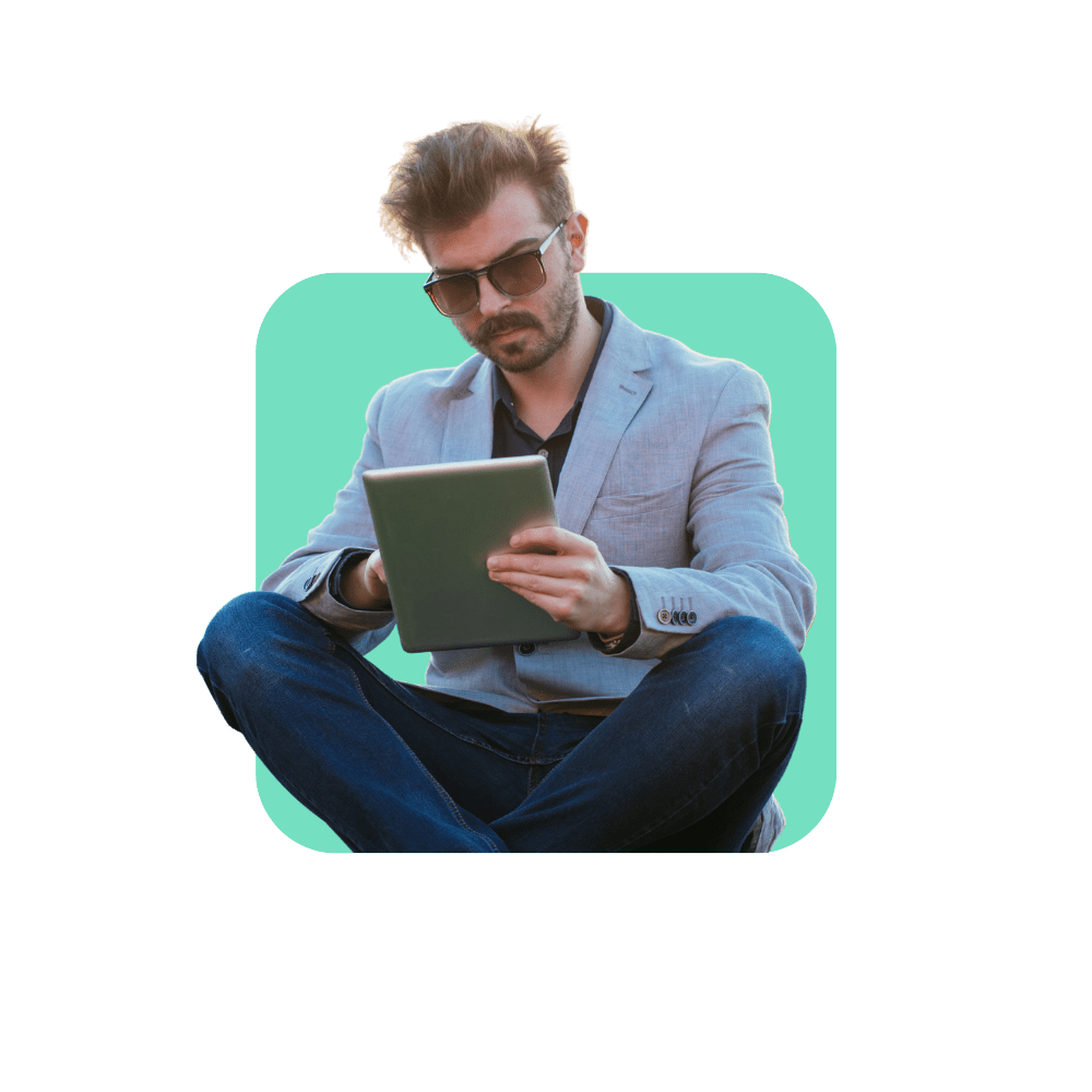 Homme avec veste grise et lunettes de soleil avec ipad à la main sur fond vert - les soft skills incontournables du manager