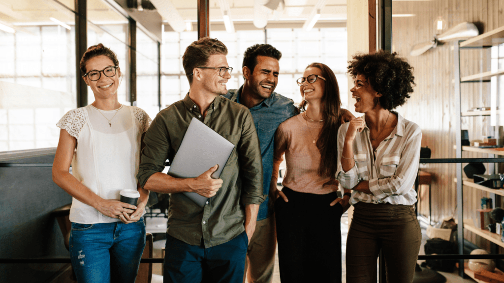 Header webinar soft skills en entreprise - Equipe dans le travail qui sourit avec ordinateur à la main