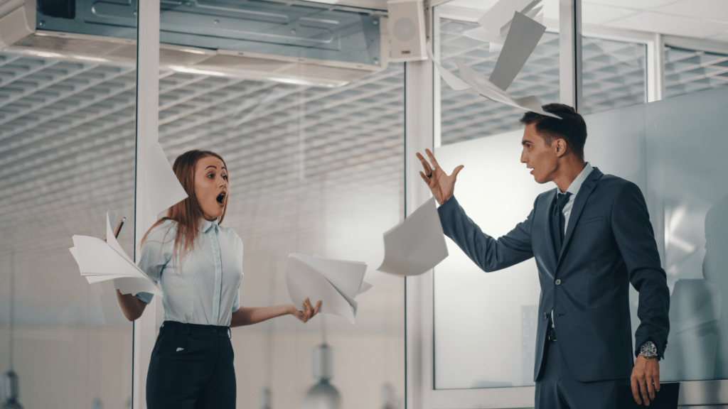 Homme qui jette des feuilles de papiers dans une bureau face à une employée - header les soft skills incontournables du manager