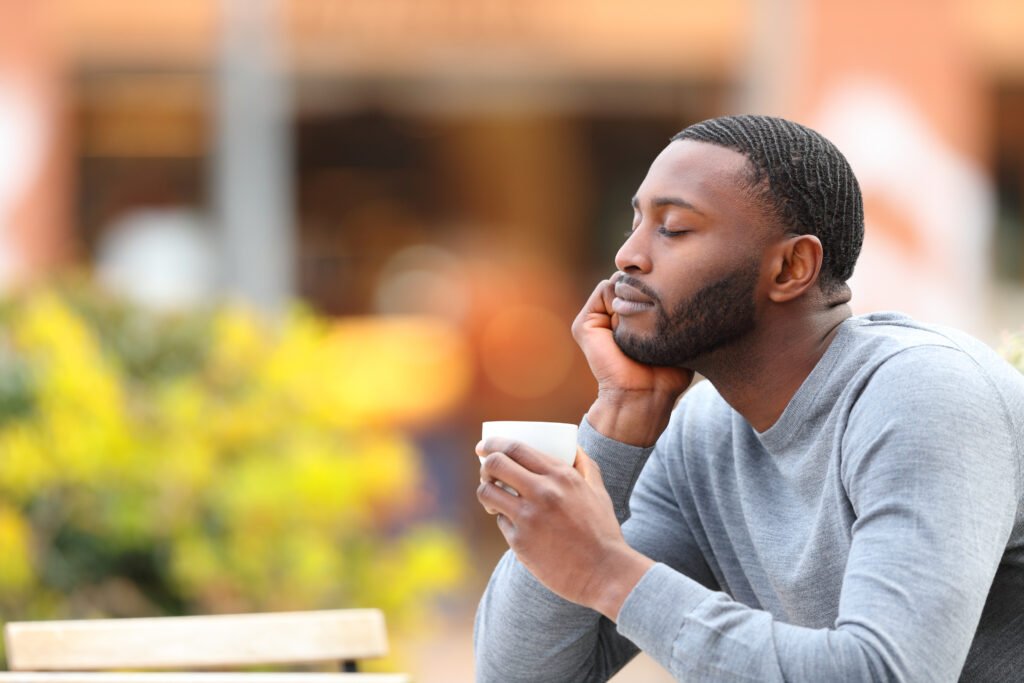 Homme noir pull gris fermant les yeux en tenant sa tasse de café - personnaliser la relation client
