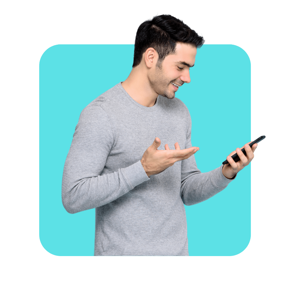 Homme avec pull gris souriant à son smartphone sur fond bleu turquoise