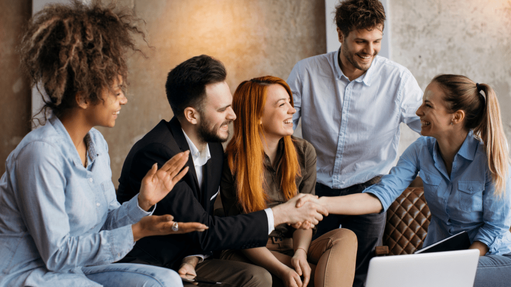 Femme qui serre la main à un homme avec groupe souriant - améliorer la relation usager