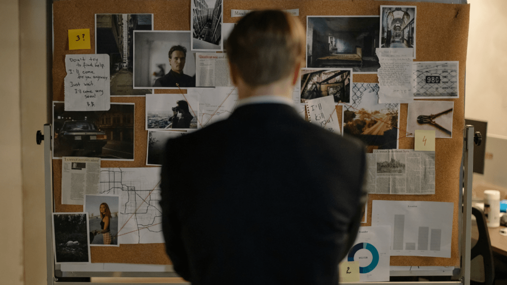 Homme de dos en costume face à un tableau enquête policière - le manager digital