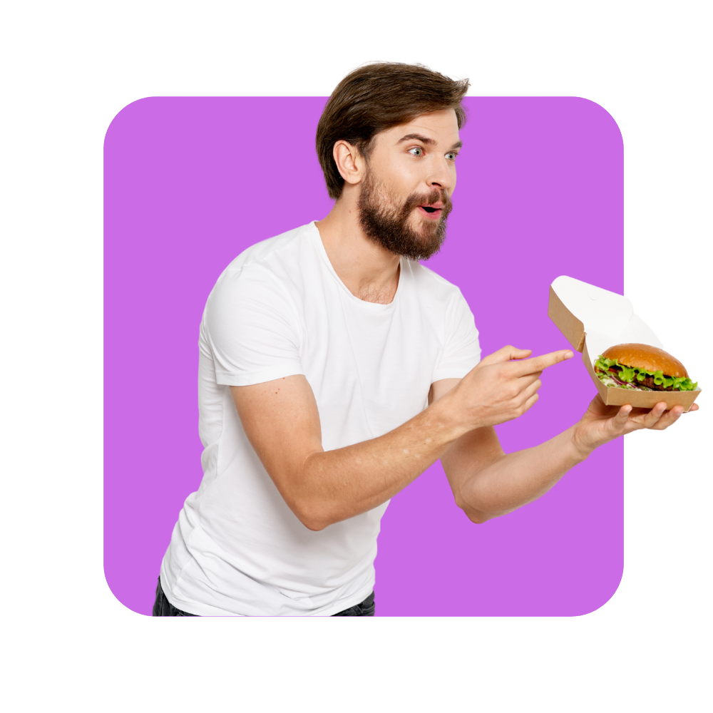 Homme avec tee shirt blanc montrant du doigt un hamburger dans un emballage carton sur fond violet