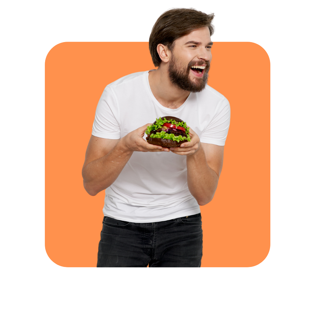 homme avec tee shirt blanc en train de rire tenant un hamburger dans ses mains sur fond orange